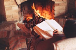 Lady reading in front of a fireplace